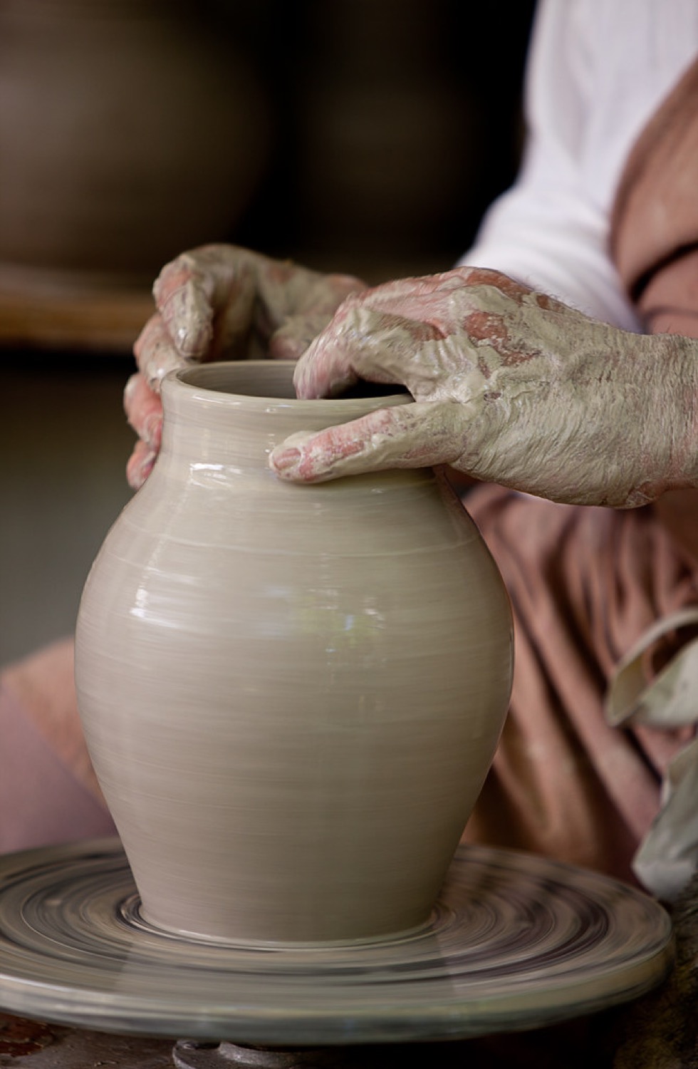 Hands shaping clay on a wheel